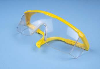 safety glasses isolated on blue  background. Concept of personal protective equipment. Medical protective glasses. Covid-19 