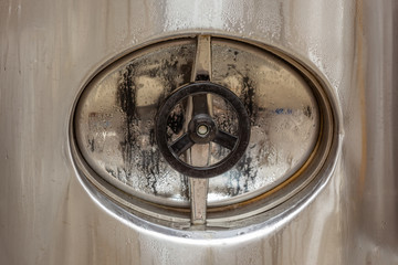 Brewery, closed hatch in a beer tank, cylinder-conical fermentation tank in drops of water