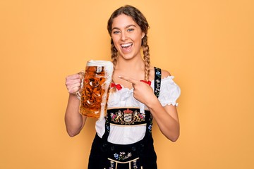 Beautiful blonde german woman with blue eyes wearing octoberfest dress drinking jar of beer very...
