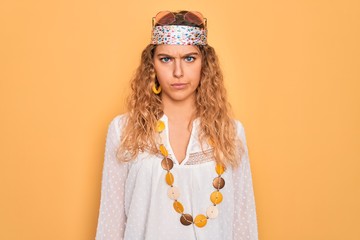 Young beautiful blonde hippie woman with blue eyes wearing sunglasses and accessories skeptic and...