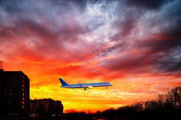 Big aeroplane is taking-off on background of sunset.
