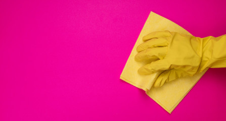 Hand in a pink (yellow) household glove with  rag wipes on colorfiul background. Professional sanitization against viruses and germs. Cleaning, desinfection concept.