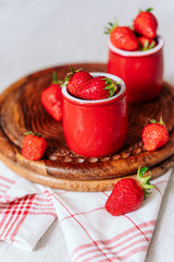 fresh strawberries in red pots on a wooden background, on a drop of water berries. healthy nutrition, vitamin charge, summer berries