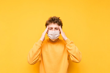 Guy in the medical mask looks at the camera and puts his fingers to his temple from the headache....
