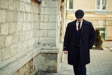 Portrait of retro 1920s english arabian business man wearing dark coat, suit, tie and flat cap.