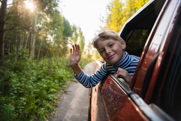 Happy kid travel by the car. He popped out of the window
