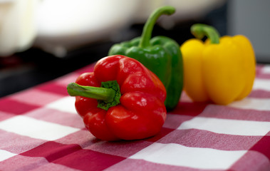 Three colored bell peppers placed on the table covered with scotch cloth
