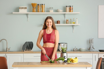 Sporty woman making smoothie in kitchen at home