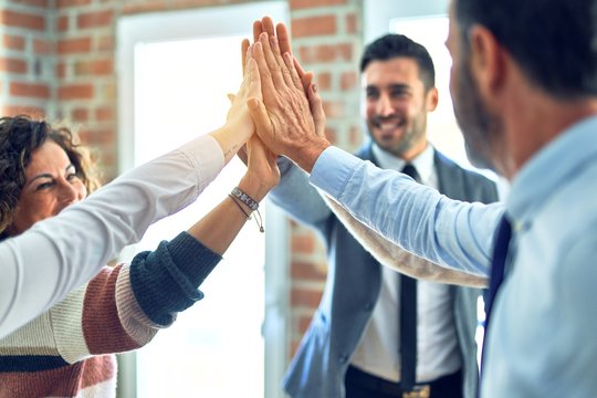 Group of business workers standing with hands together highing five at the office