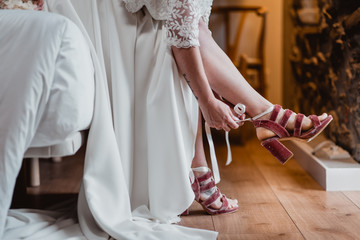 woman in wedding dress putting on shoes