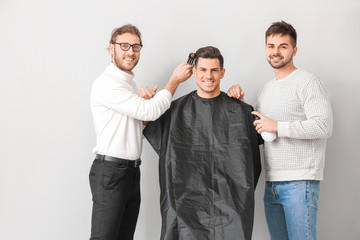Young hairdressers working with client against white background