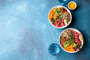 Raw Tuna quinoa health salad with vegetables on blue background