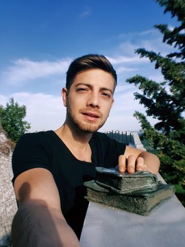 Bel ragazzo caucasico mentre si scatta un selfie con una statua di libri