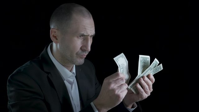 Financial crisis. Afflicted business man holding money in his hands.