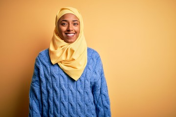 Young African American afro woman wearing muslim hijab over isolated yellow background with a happy and cool smile on face. Lucky person.