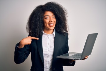 Young african american business woman with afro hair using computer laptop from job with surprise face pointing finger to himself
