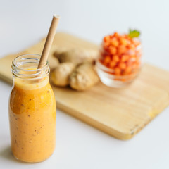Bright sea buckthorn smoothie on a rustic board. berries, ginger, glass bottles, paper tubes. no plastic. healthy food