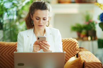 female with laptop writing sms in modern house in sunny day