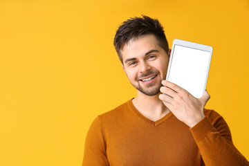 Young man with tablet computer on color background