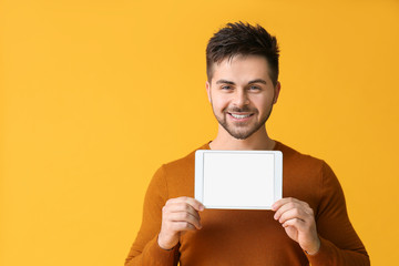 Young man with tablet computer on color background