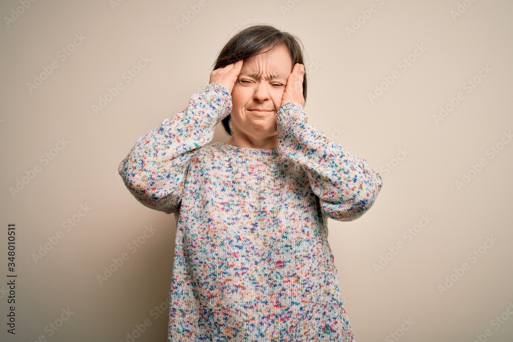 Sticker Young down syndrome woman standing over isolated background suffering from headache desperate and stressed because pain and migraine. Hands on head.