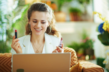 happy elegant female with laptop and two lipsticks vlogging