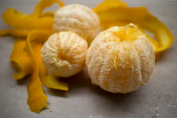 three peeled oranges with zest around lie on a gray kitchen table 