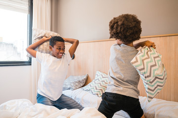 Two brothers playing with pillows at home.