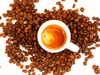 espresso on a bed of coffee.Roasted coffee beans background.Cup of coffee on beans