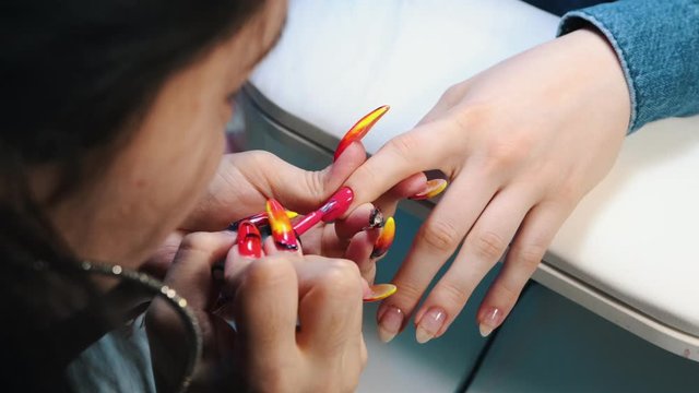 Doing manicure in the beauty salon - applying pink nail polish
