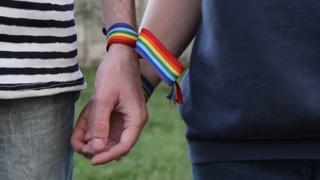 hands with rainbow LGBT ribbons on the wrists. gay couple gently holds hands and stroking each other
