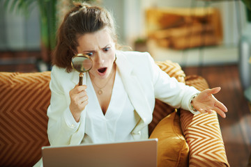 surprised modern woman with laptop and magnifying glass