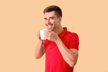 Young man with cup of hot coffee on color background