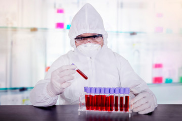 Scientist holding blood tube from its rack in lab