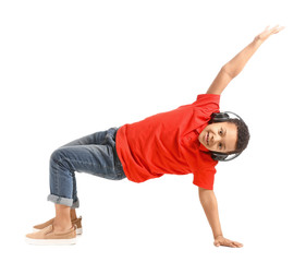 Little African-American boy listening to music and dancing against white background