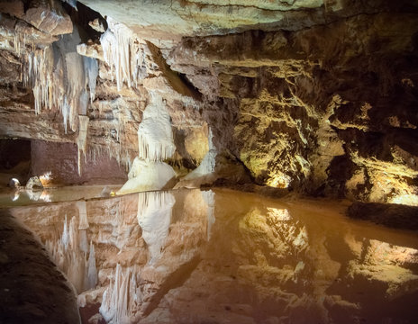 Stalactites et stalagmites dans une cavit&eacute; souterraine avec un miroir d'eau