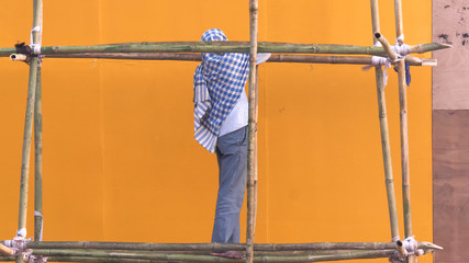 worker standing on bamboo scaffolding near india gate in new delhi