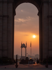 shot of the sun and canopy behind india gate at sunrise in new delhi