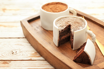 Chocolate cakes in shape of coffee cups on white wooden background