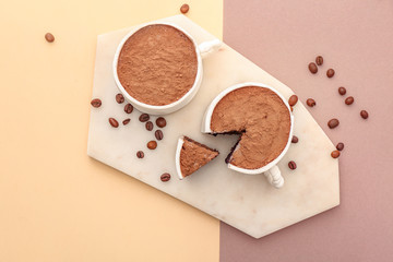 Chocolate cakes in shape of coffee cups on color background