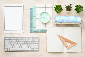 Tablet computer, PC keyboard, alarm clock and stationery on grey background