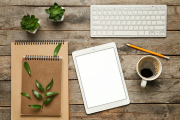Tablet computer, PC keyboard, cup of coffee and stationery on wooden background