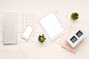 Tablet computer, mobile phone, PC keyboard, alarm clock and stationery on wooden background