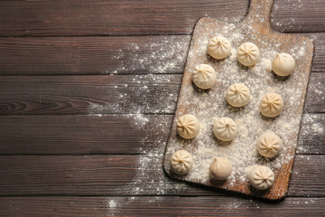 Board with raw dumplings on table