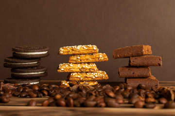 Cookies on a brown background of a burnt tree with coffee grains scattered on the table. Side view, copy space.