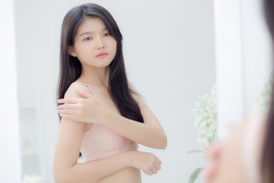 Beautiful sexy young asian woman look mirror applying cream on shoulder and message, beauty girl applying body lotion skin care for health and soft hydration, treatment and cosmetic with moisturizer.