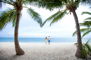 Romantic couple in love hugging, kissing and running on the sandy tropical Caribbean beach in Dominican republic landscape  