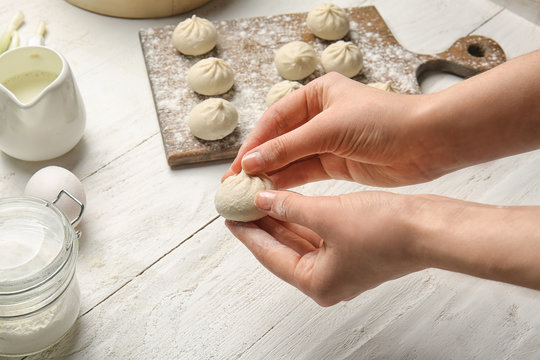 Woman preparing tasty dumplings on table