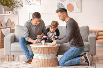 Happy gay couple with adopted child playing at home