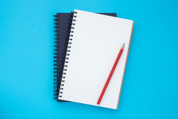 Top view above of two spiral notebooks that open and close, stacked with pencil  isolated on light blue background for design a mockup. Education and business concept. flat lay